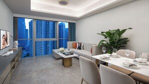 A modern living room with a dining area, large windows with a city view, and a ceiling light fixture. - Star Residence ICC Guangzhou (Guangzhou)