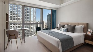 A modern hotel room with a large bed, a desk, and a view of high-rise buildings. - Star Residence ICC Guangzhou (Guangzhou)