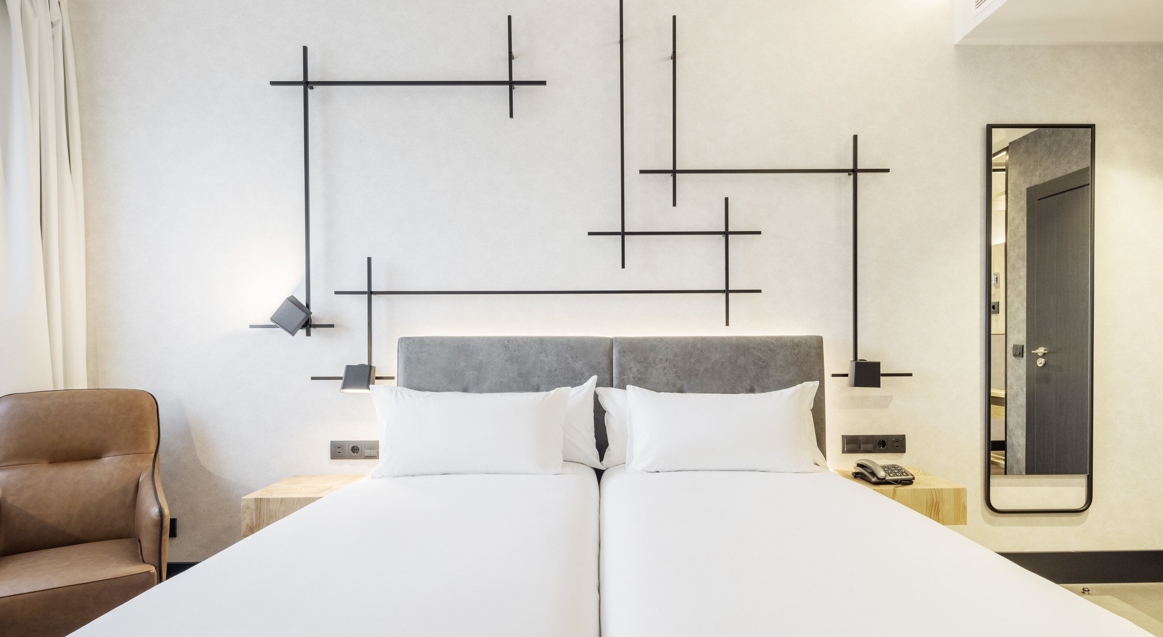 Una habitación de hotel moderna con una cama grande, una silla y un espejo en la pared.