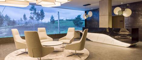 A modern interior with a large window, a round table with four chairs, and a unique ceiling light fixture.