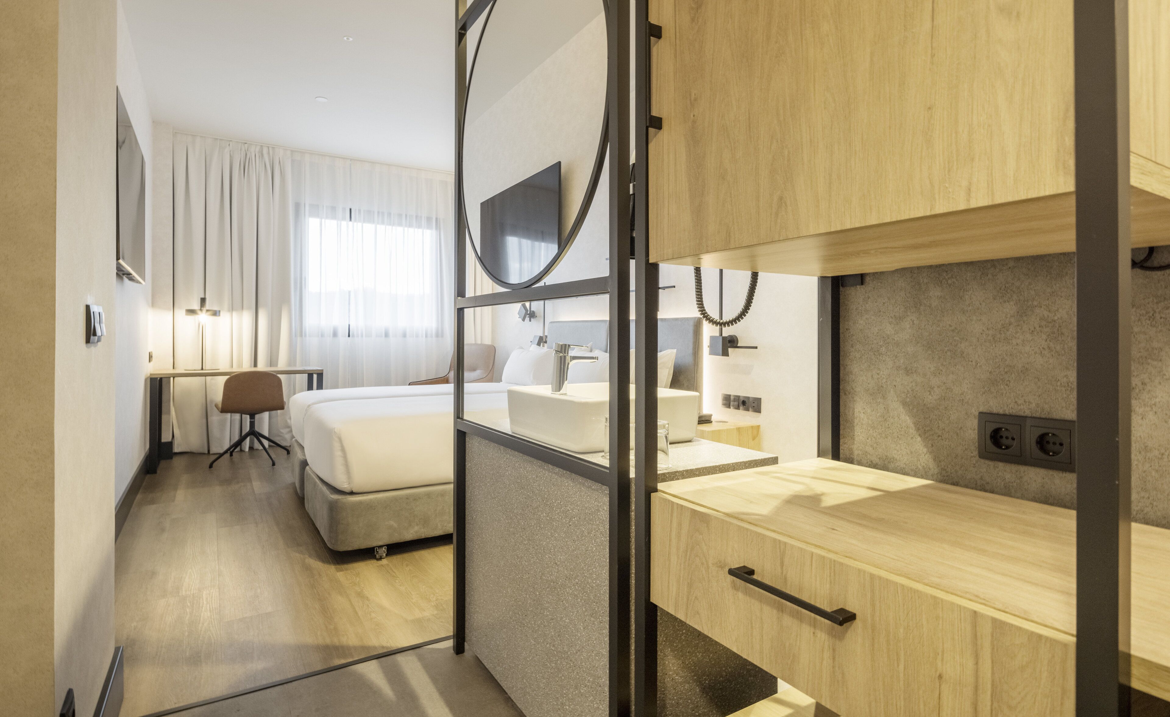 Una habitación de hotel moderna con cama, escritorio y baño.