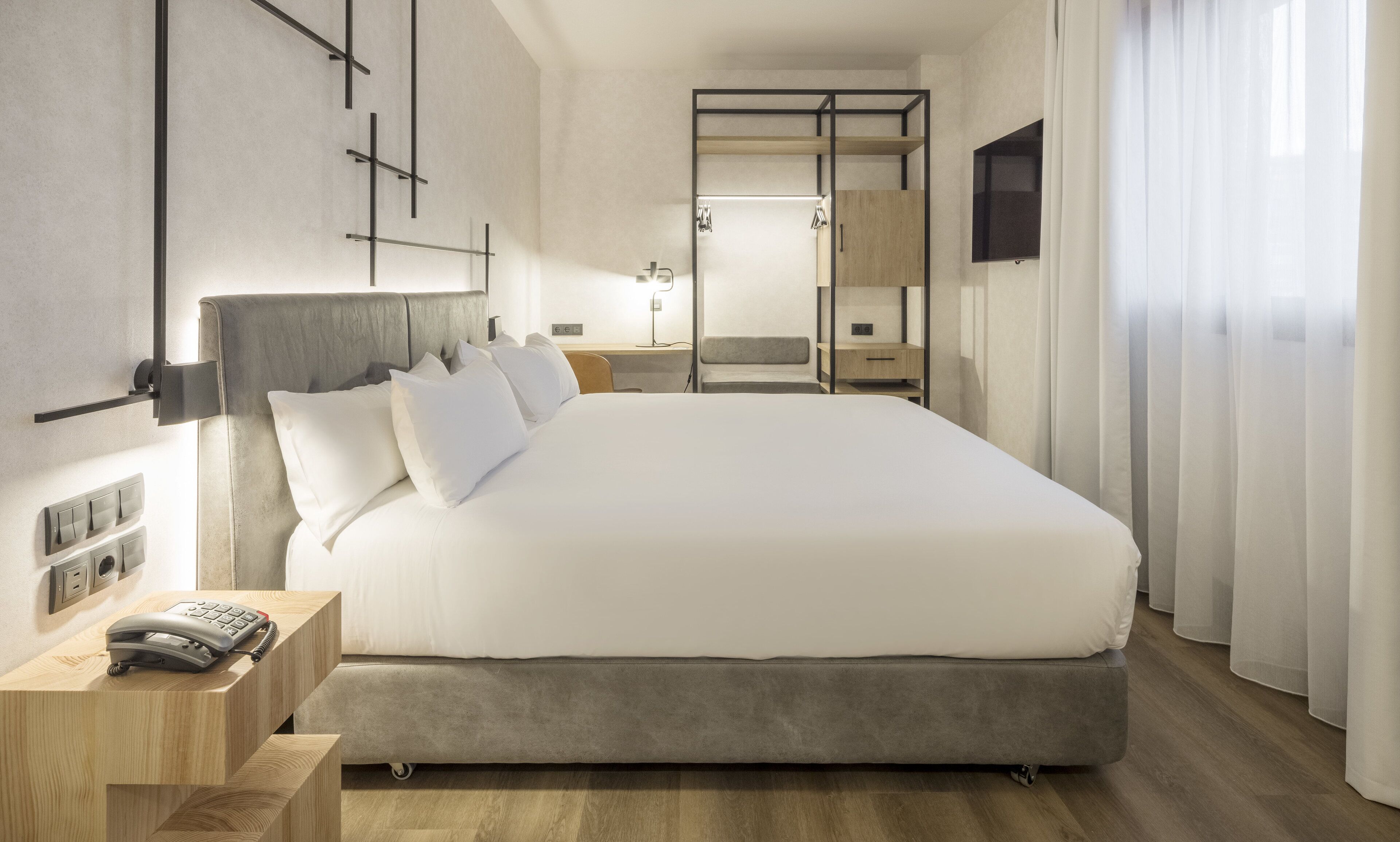 Une chambre d’hôtel moderne avec un grand lit, des tables de chevet, un bureau et une télévision.