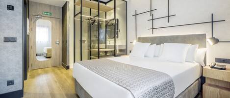 Una habitación de hotel moderna con una cama grande, un vestidor y zona de ducha.