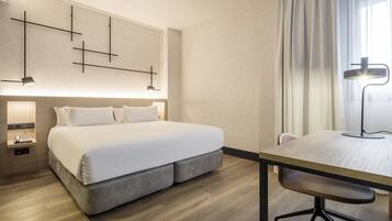 Ett hotellrum med en stor säng, sängbord, ett skrivbord med en stol och en modern väggdesign.