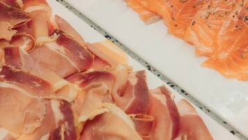 A variety of cured meats, including prosciutto and salami, displayed on a white surface.