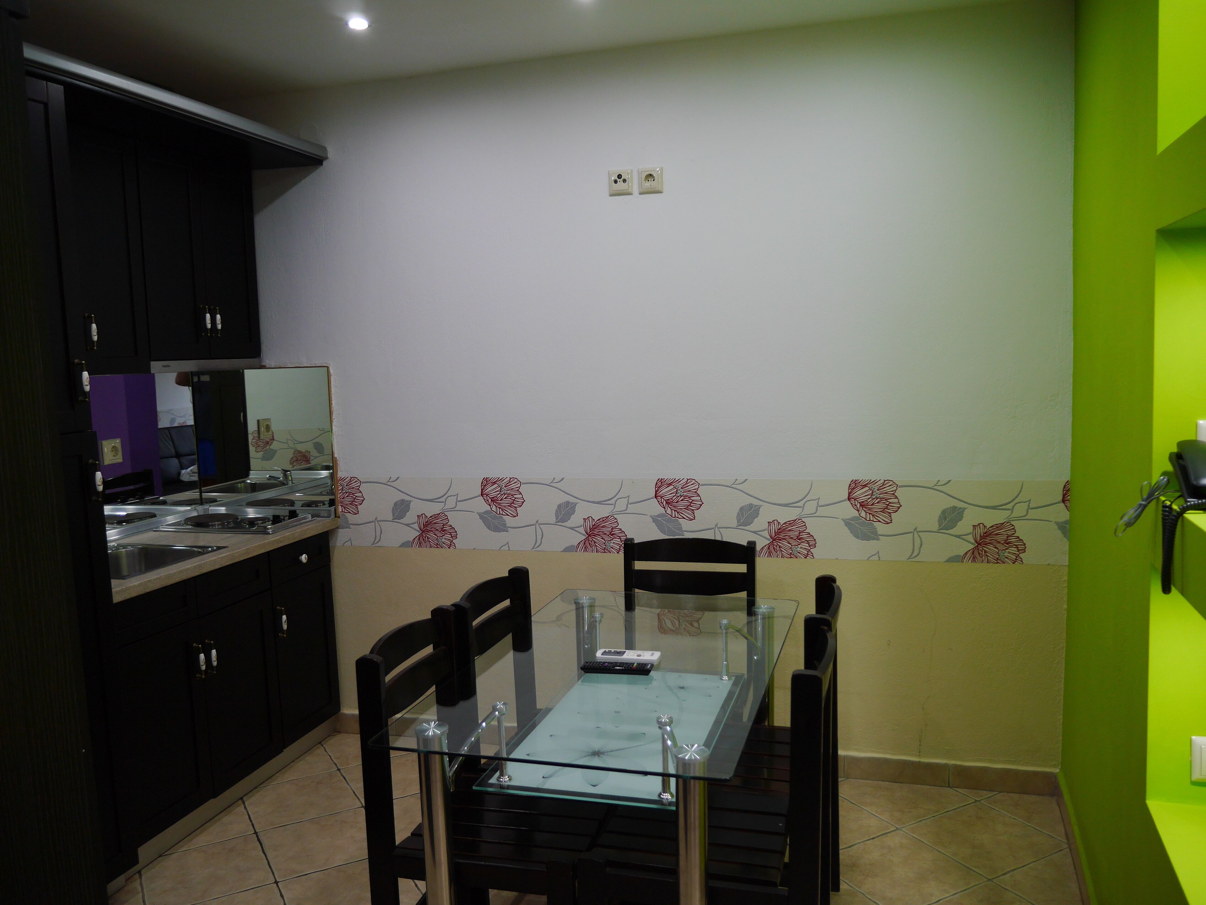 A compact kitchen with dark cabinets, a glass-top dining table, and chairs.
