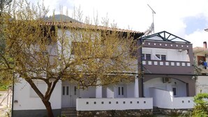 A two-story building with a white facade, a stone base, and a sloped roof.