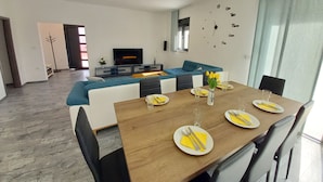 A modern living room with a sofa, TV, and dining area with a table set for four. - Brand new villa with private pool on peaceful location (Vodnjan)