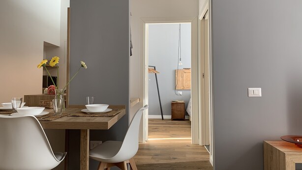 Ein Essbereich mit einem Holztisch, weißen Stühlen und einer Blumenvase.