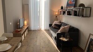 Ein modernes Wohnzimmer mit Sofa, Couchtisch, Fernseher und einem Essbereich mit Tisch und Stühlen.