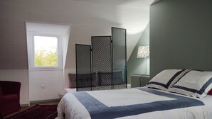 Une chambre à coucher avec un lit, une fenêtre, un fauteuil rouge et un paravent décoratif.