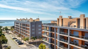 A multi-story hotel with balconies, a parking lot, and a view of the sea. - 2-Bedroom Luxury Apartment with Rooftop Pool, Village Marina, Olhão (Olhão)