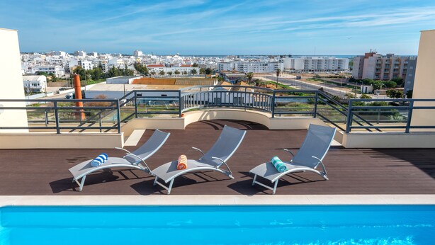 A rooftop pool area with three lounge chairs and a clear view of the cityscape. - 2-Bedroom Luxury Apartment with Rooftop Pool, Village Marina, Olhão (Olhão)
