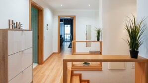 A modern hallway with a wooden bench, a potted plant, and a 'HOME' sign on a cabinet. - 2-Bedroom Luxury Apartment with Rooftop Pool, Village Marina, Olhão (Olhão)