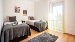 A bedroom with two beds, a large window, and a view of the outside. - 2-Bedroom Luxury Apartment with Rooftop Pool, Village Marina, Olhão (Olhão)
