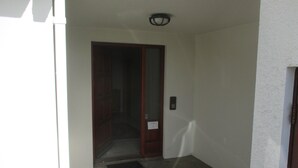 Ein schmaler Eingang mit einer Holztür und einer kleinen Stufe.