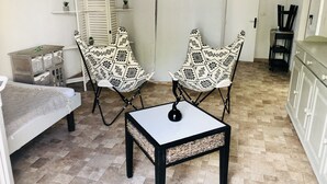 A small, cozy room with two patterned chairs, a small table, a sofa, and a cabinet. - Bungalow La Colline aux Moulins (Sainte-Anne)