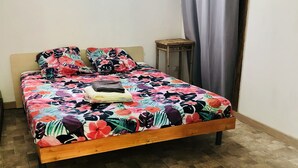 A bed with a floral bedspread, a wooden headboard, and a small wooden table beside it. - Bungalow La Colline aux Moulins (Sainte-Anne)