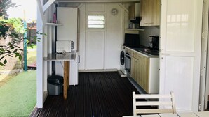 A compact kitchen with a washing machine, a small table, and a chair. - Bungalow La Colline aux Moulins (Sainte-Anne)