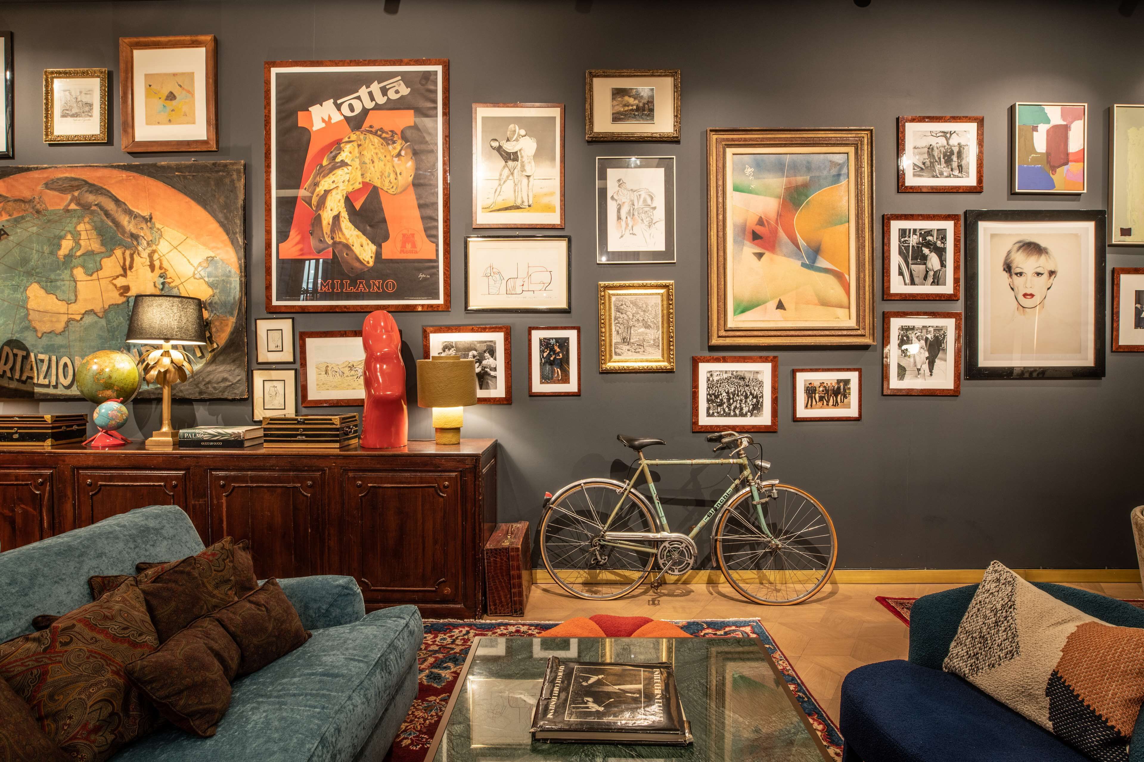 Un soggiorno con un divano blu, un tavolino, una bicicletta e diverse opere d'arte appese al muro.