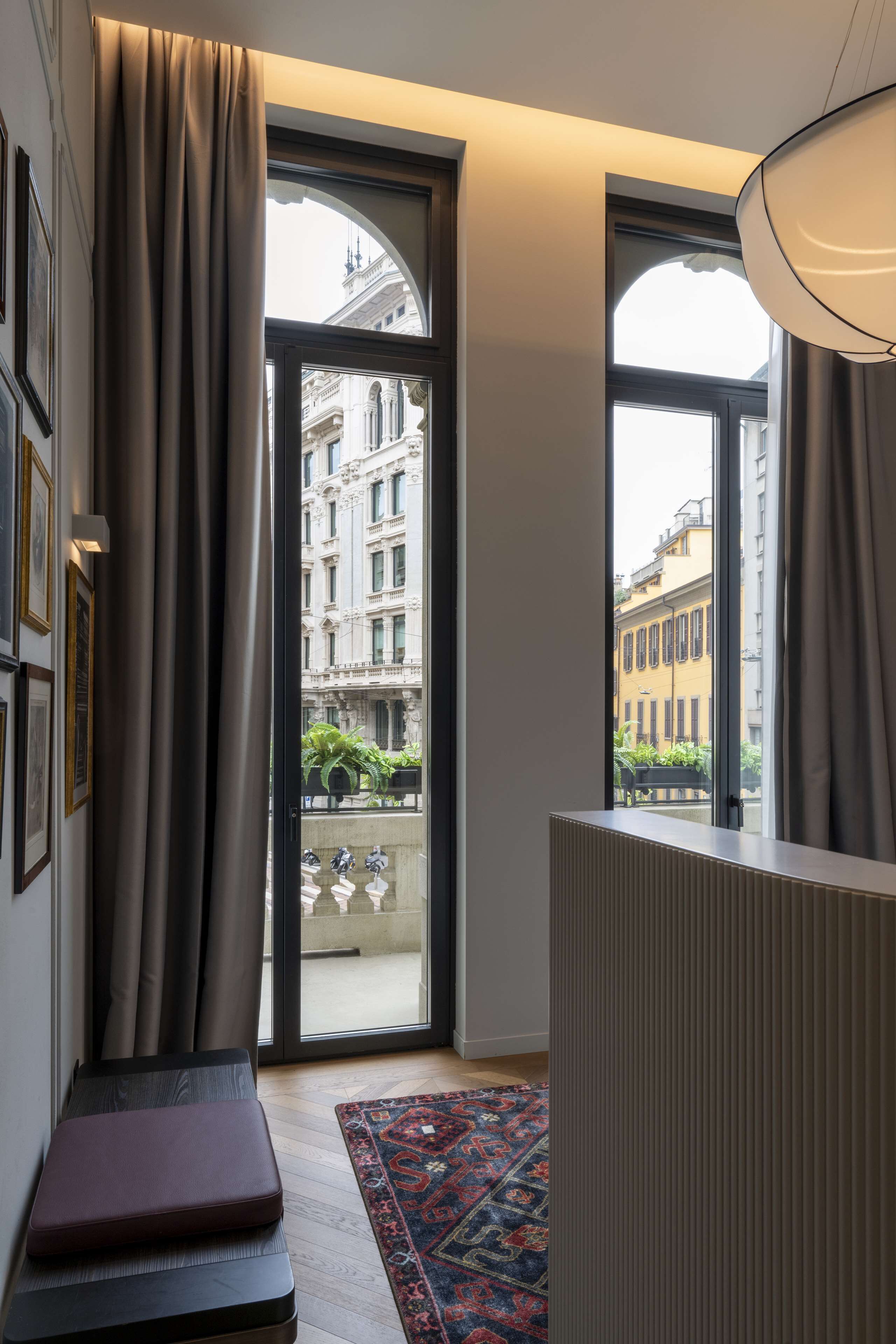 A room with a large window, a radiator, a bench, and a patterned rug.