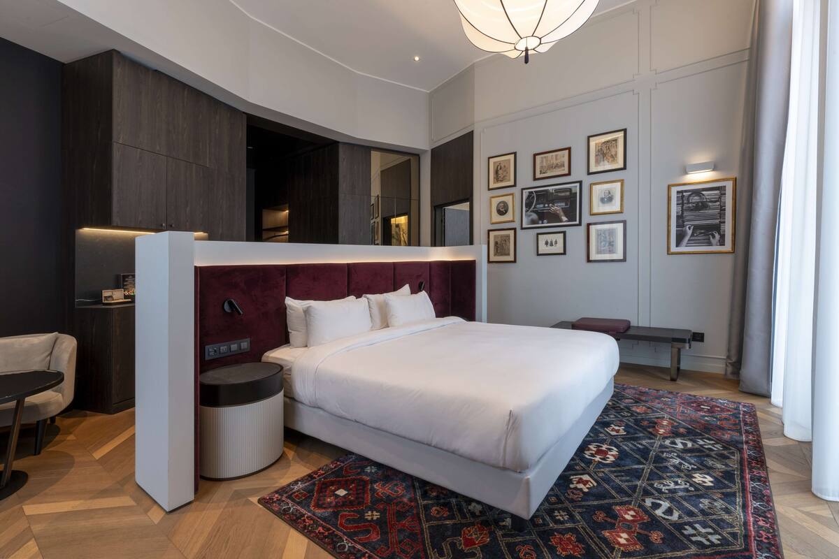 A modern hotel room with a large bed, a desk, and a seating area.