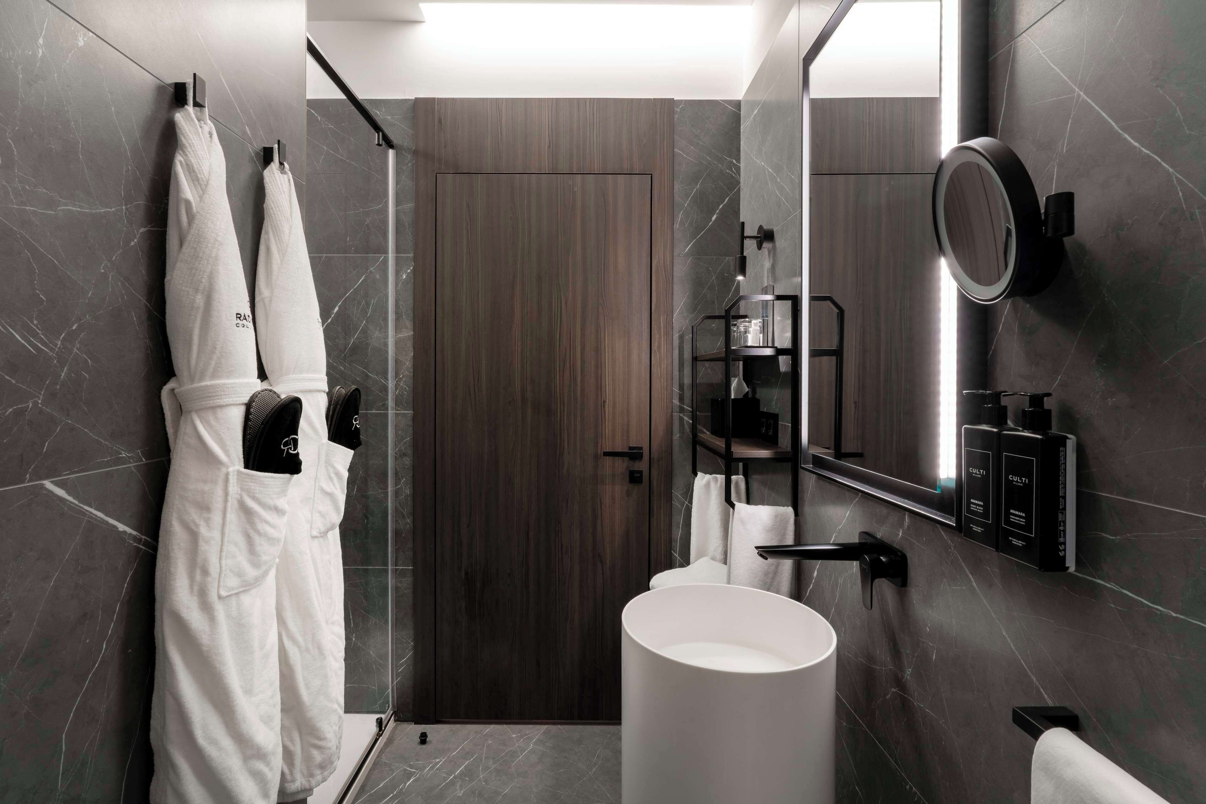 A modern bathroom with a large mirror, a white sink, and a shower area.