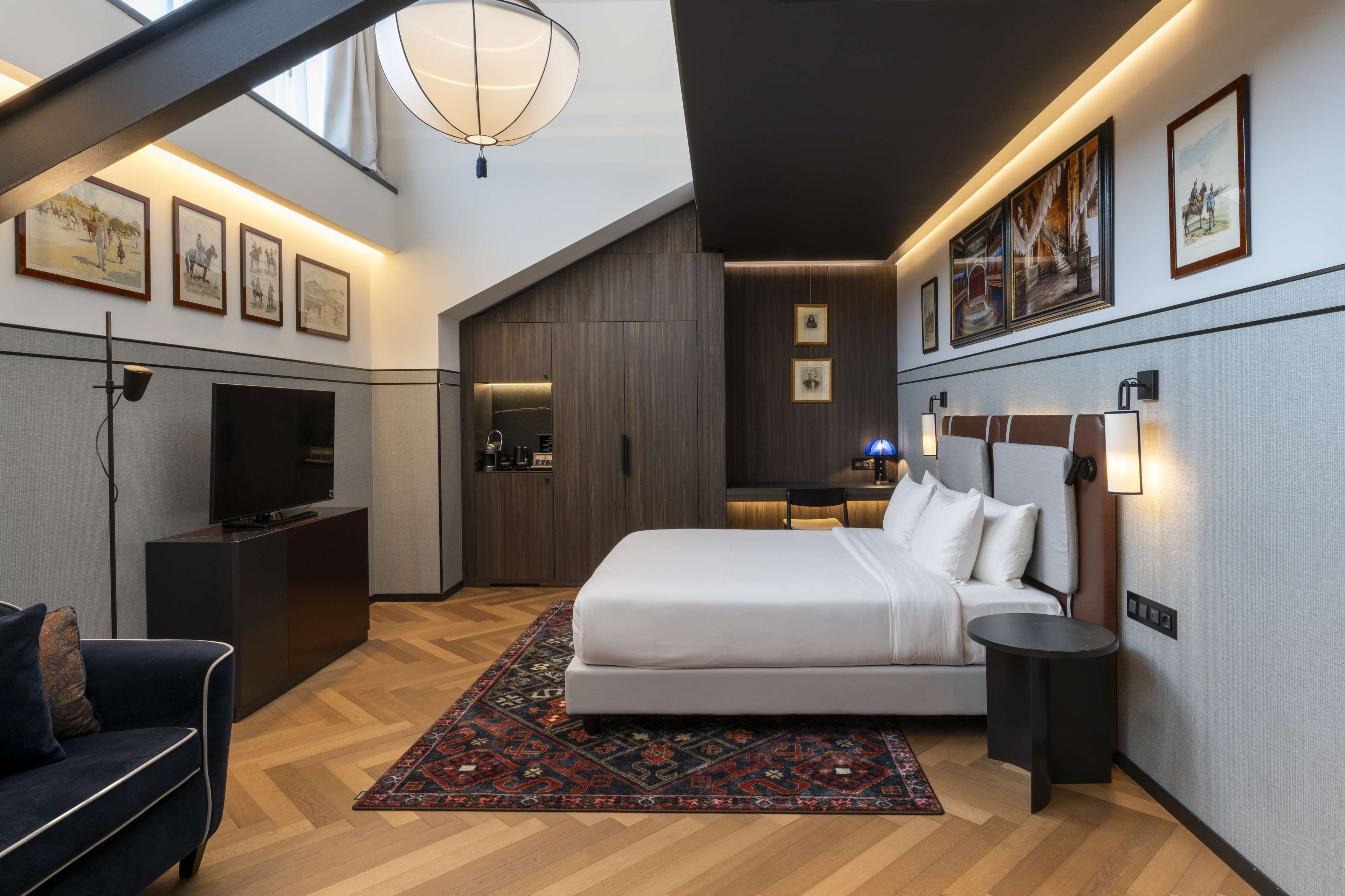 A modern hotel room with a large bed, a TV, a desk, and a walk-in closet.