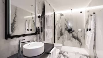 Un baño moderno con un espejo grande, un lavabo redondo, un inodoro y una zona de ducha.