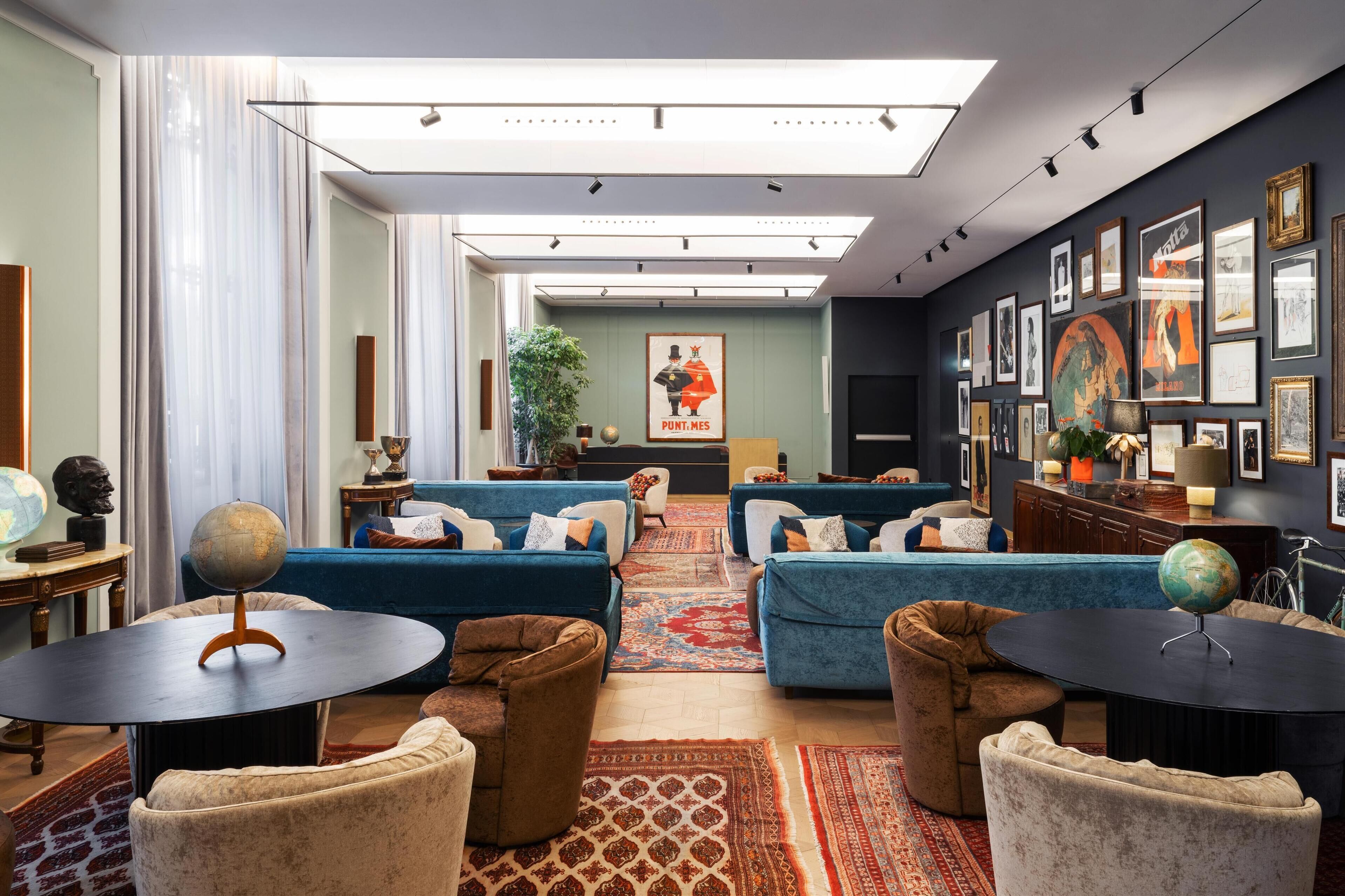 A modern lounge area with blue sofas, a globe on a stand, and a large poster on the wall.
