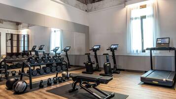 Un gimnasio con varios equipos de ejercicio, como mancuernas, kettelbells, una prensa de banca y cintas de correr.