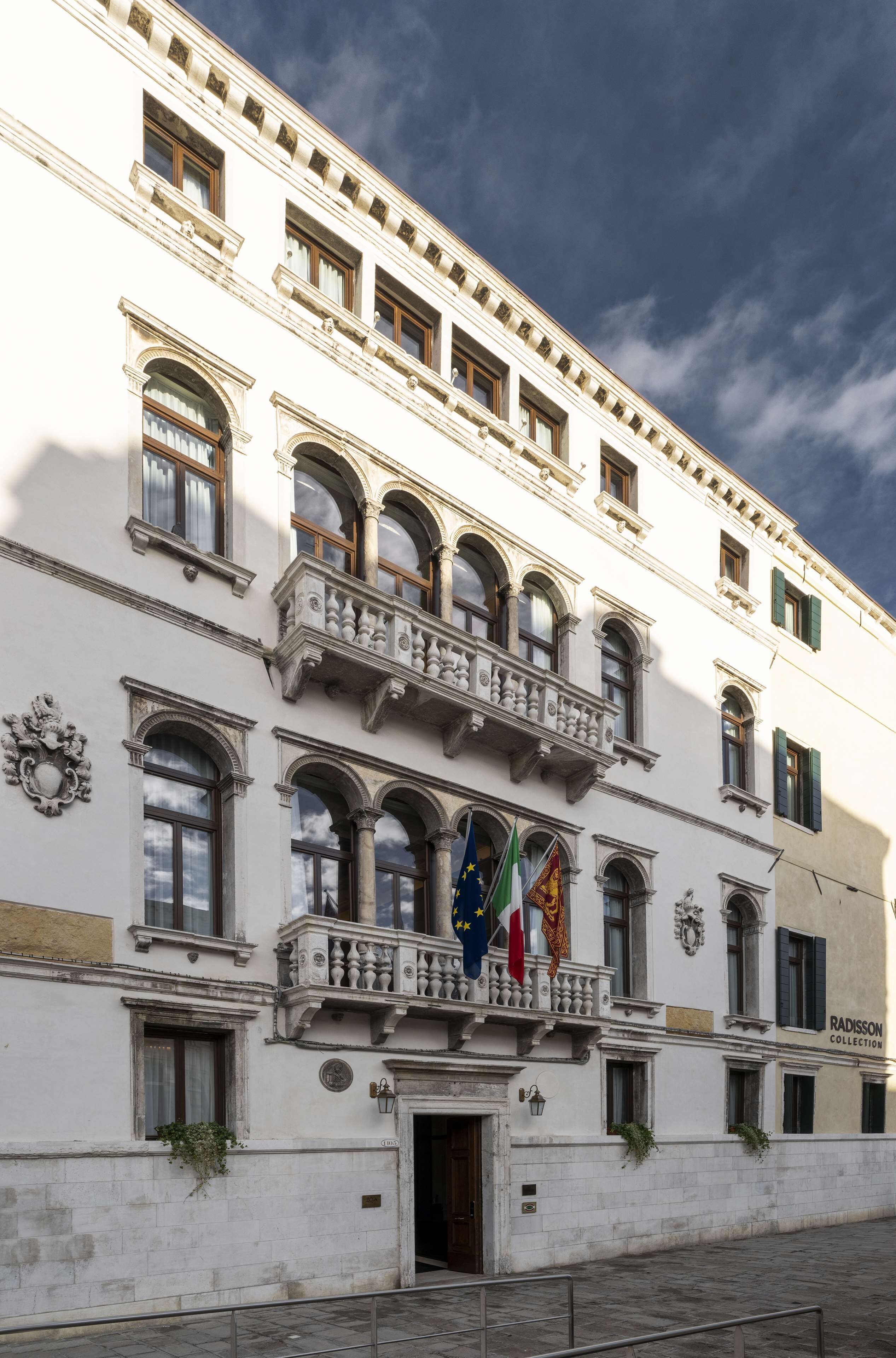 Un edificio histórico con varios balcones, ventanas de arco y banderas.