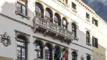 Un edificio histórico con varios balcones, ventanas de arco y banderas.