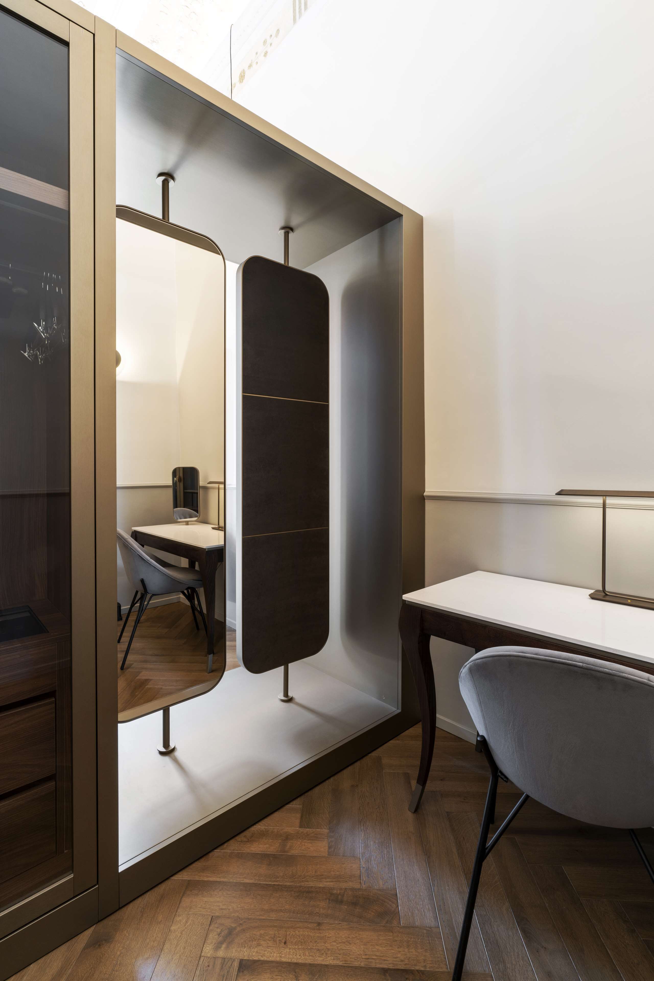 Une chambre moderne avec un plancher en bois, un bureau avec une chaise et un grand miroir.