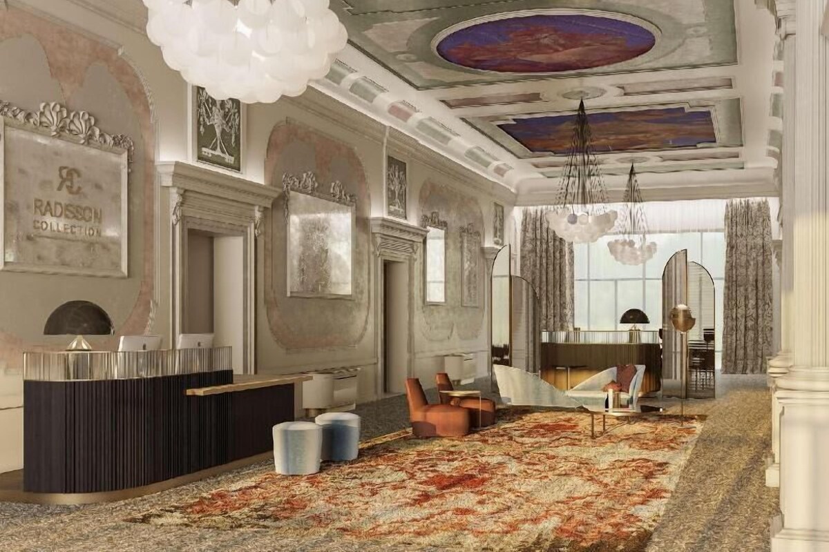 A spacious lobby with a large, patterned carpet, a reception desk, and a seating area with chairs and tables.