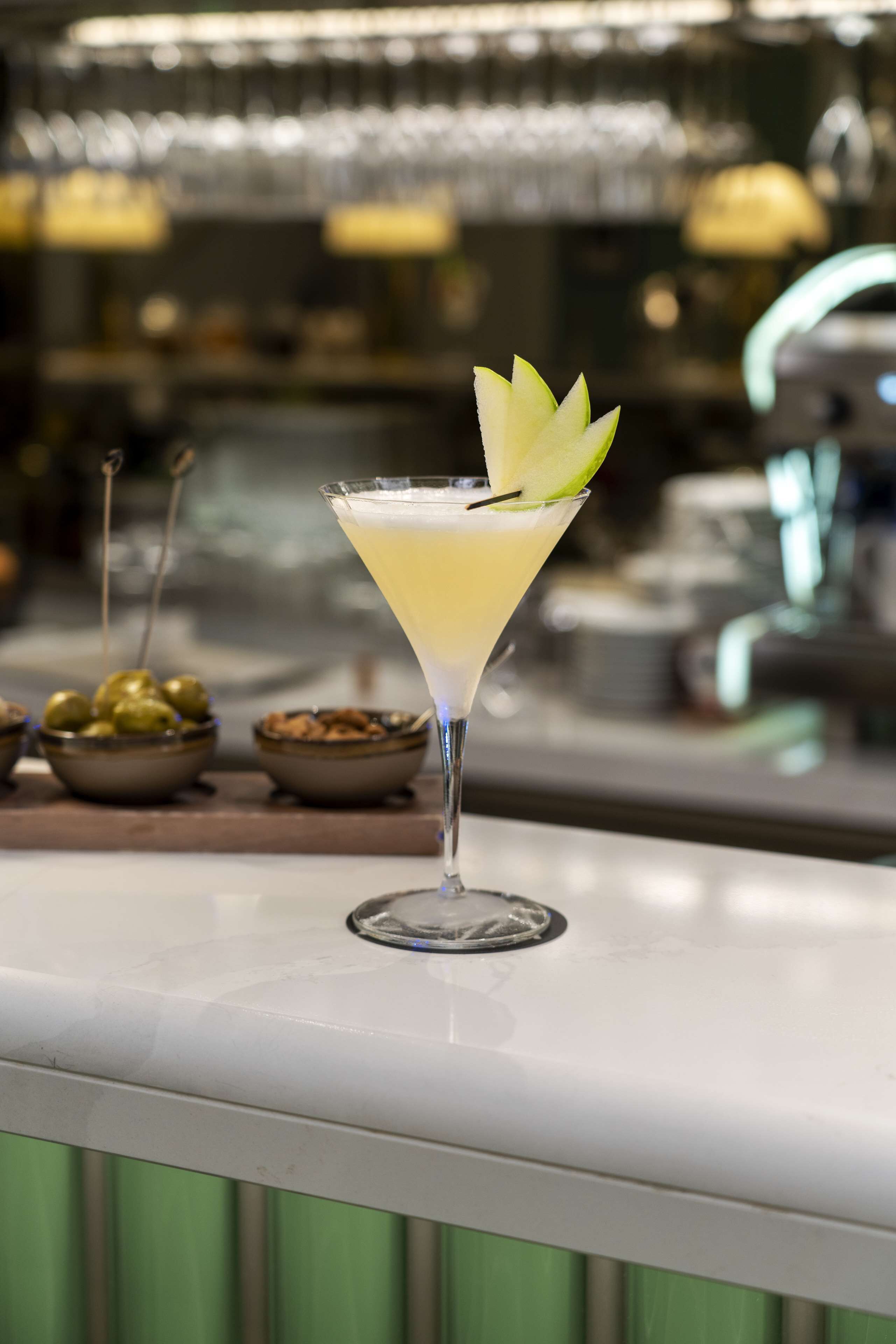 A martini glass with a lime garnish on a bar counter.