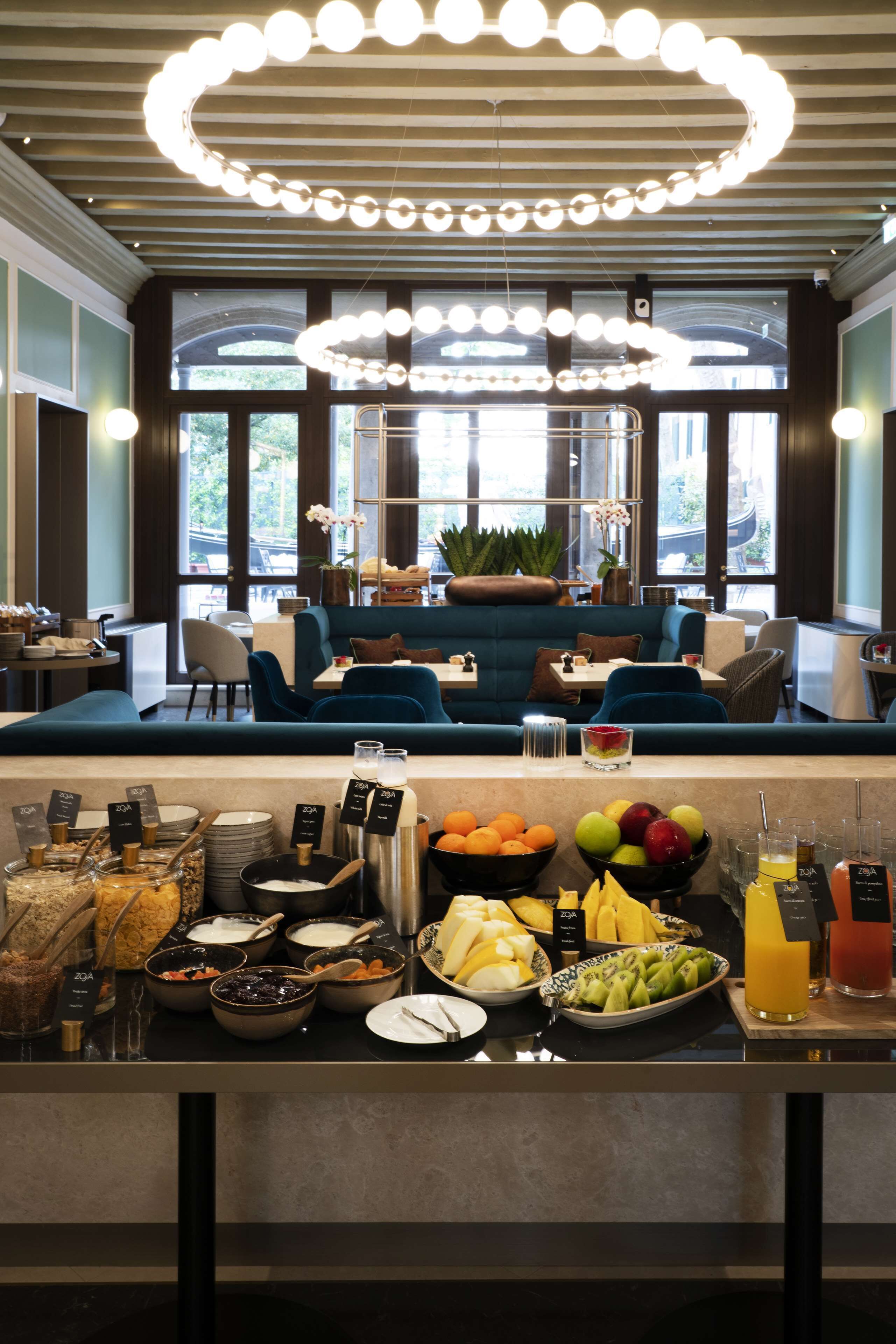 Ein Frühstücksbuffet mit verschiedenen Speisen und einem Sitzbereich mit blauen Sofas und einem Chandelier.