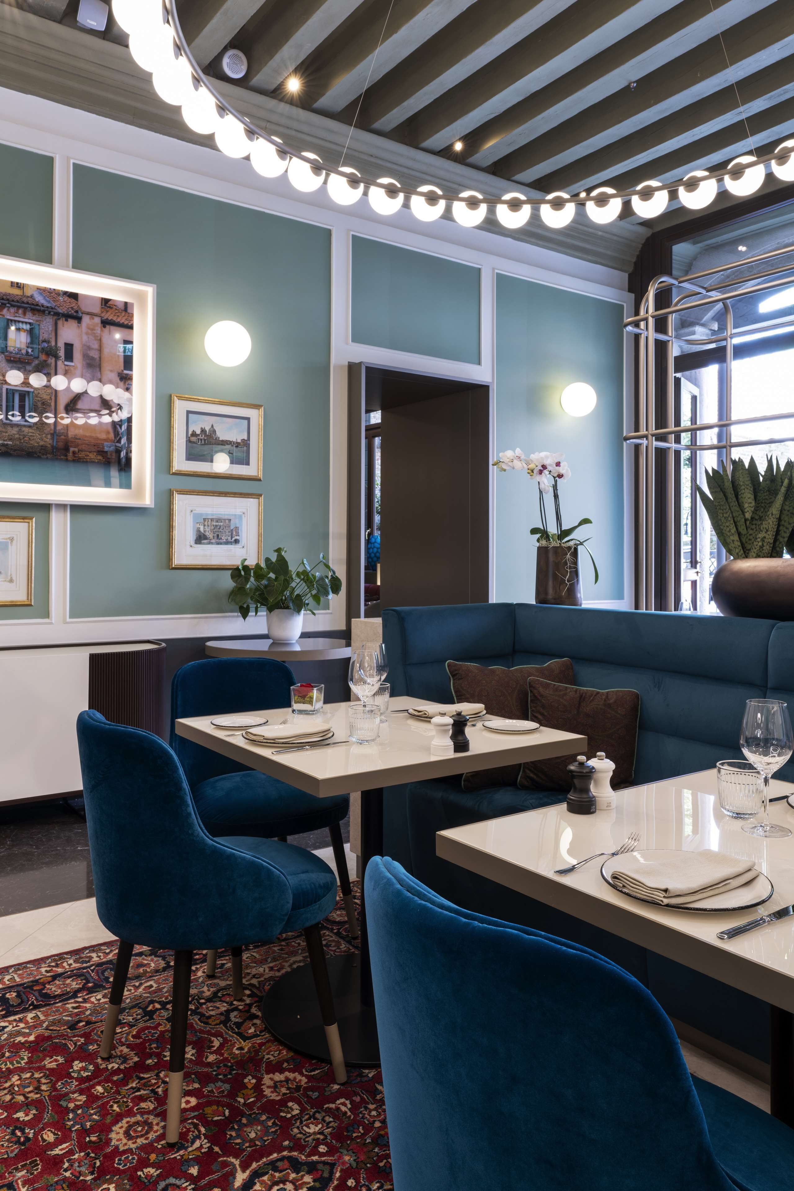 A restaurant with a blue upholstered booth, round tables, and blue chairs.