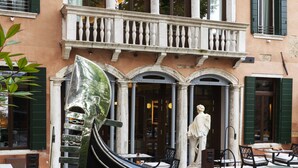 A courtyard with a black gondola sculpture, outdoor seating, and a statue. - Radisson Collection Hotel, Palazzo Nani Venice (Venice)