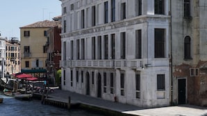 A canal with boats docked, a white building with classical architecture, and a yellow building with a red awning. - Radisson Collection Hotel, Palazzo Nani Venice (Venice)