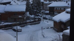 Un pueblo cubierto de nieve con edificios, un camino de tierra y un gran árbol.