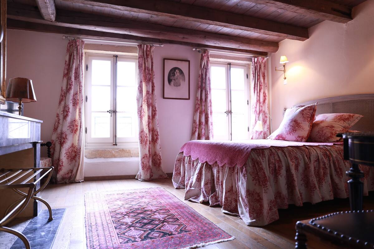 A bedroom with a bed, a bench, a rug, and a lamp.