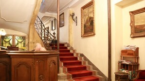 Uma escadaria com carpete vermelho, paredes de madeira e um candelabro.