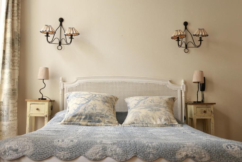 Un dormitorio con una cama blanca, dos lámparas a juego en mesitas de noche y una manta decorativa.