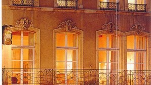 Um hotel com várias varandas, um café no nível da rua e uma placa indicando local para troca de roupa.