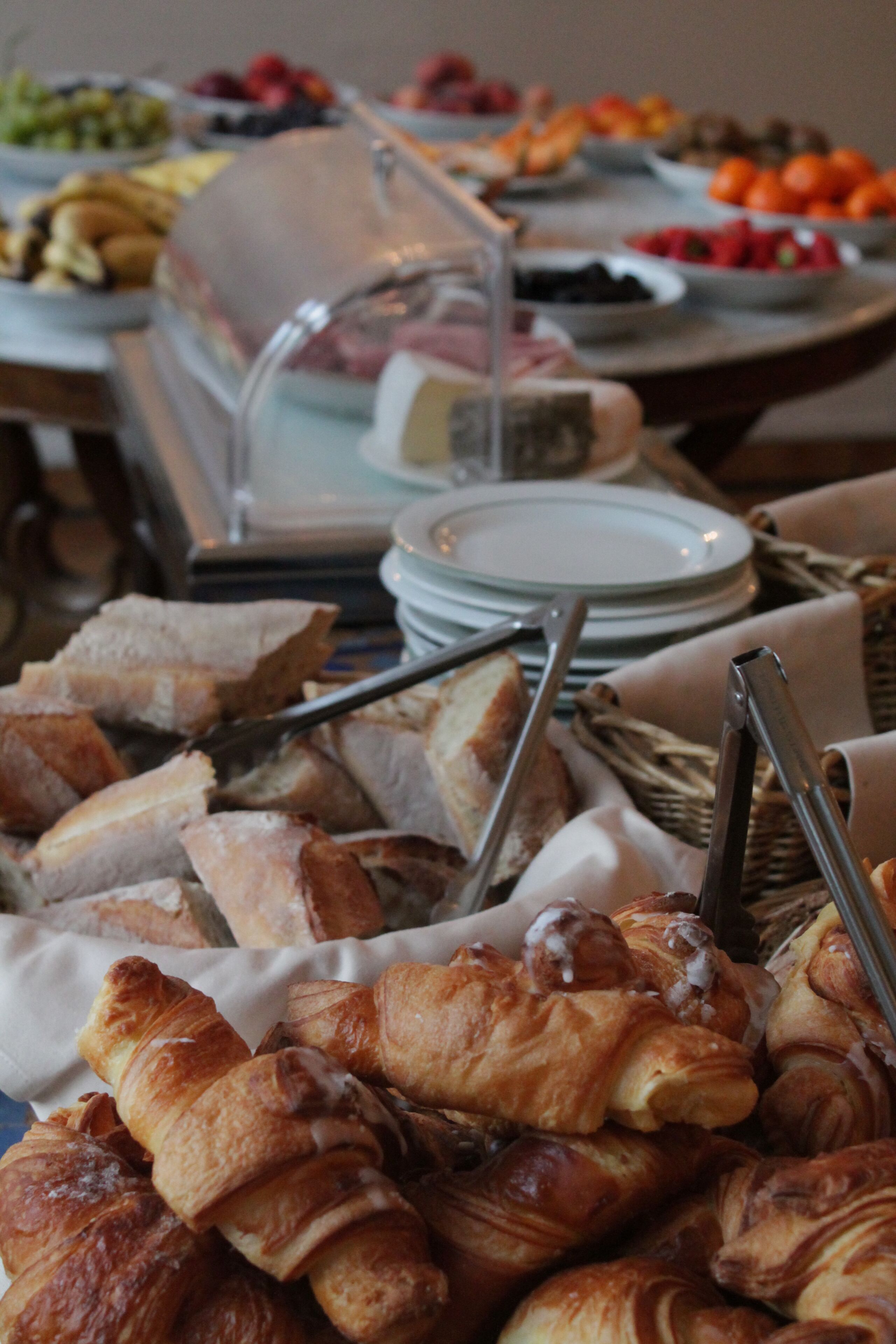 Een buffet met diverse gerechten, waaronder brood, gebak en fruit.