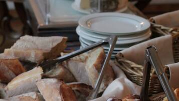 Een buffet met diverse gerechten, waaronder brood, gebak en fruit.
