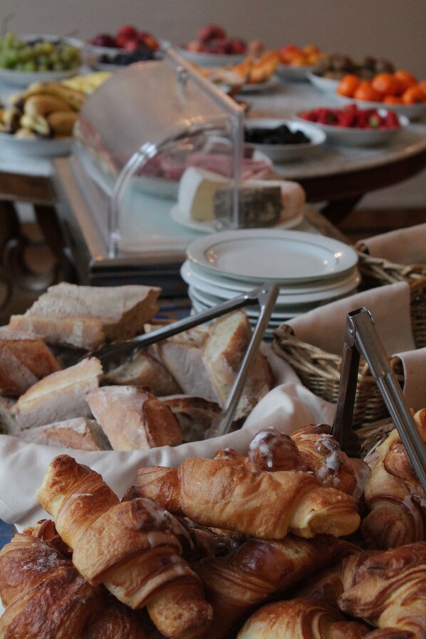 A buffet with various food items including bread, pastries, and fruits. - Hotel De La Cathedrale (Metz)
