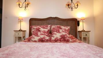 A bed with a floral bedspread and two matching pillows, flanked by two bedside tables with lamps and a telephone.