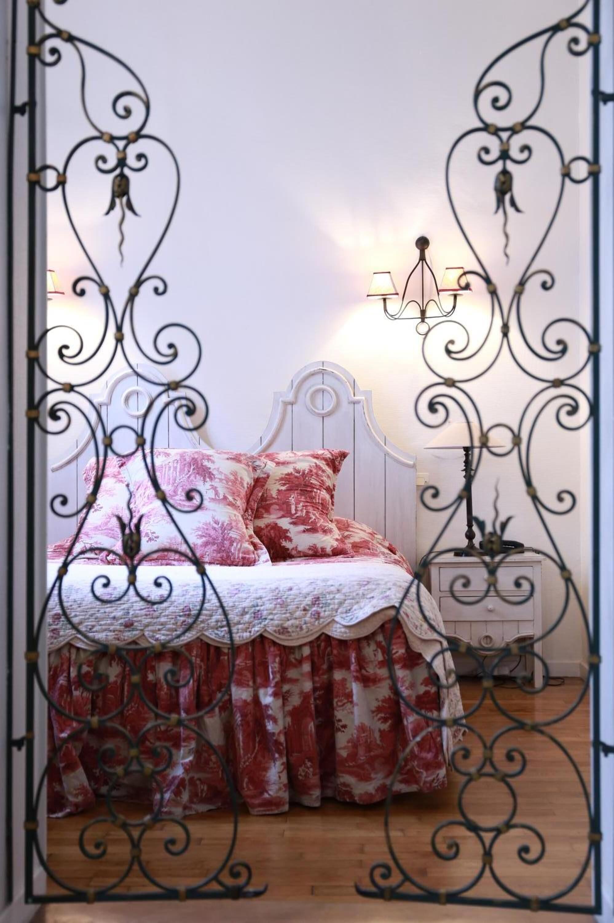 A bedroom with a bed, a nightstand, and a chandelier.
